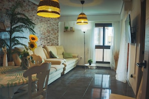 A living room with a sofa, a dining table, and two hanging lamps.