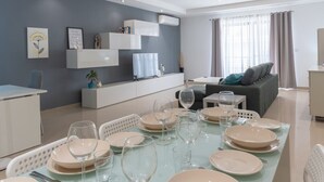 En moderne stue med spiseplads, grå vægge og en sofa.