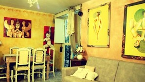 A living room with a sofa, chairs, a table, and artwork on the walls. - Serragli - Art Flat (Florence)