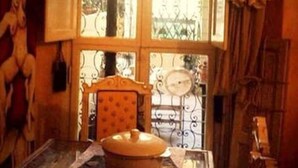 A room with a wooden table, a chair, a window with a view of greenery, and a statue on the wall. - Serragli - Art Flat (Florence)