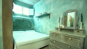 A bedroom with a bed, a dresser, a mirror, and a shelf with books and decorative items. - Serragli - Art Flat (Florence)