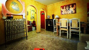 A room with a patterned floor, a dining area with chairs and a table, a red door, and a painting on the wall. - Serragli - Art Flat (Florence)