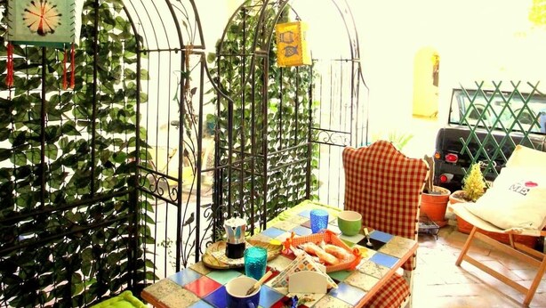A rustic outdoor dining area with a table set for two, surrounded by metal arches and greenery. - Serragli - Art Flat (Florence)