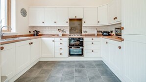 A kitchen with white cabinets, a double oven, and a window.