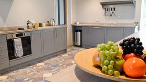 A modern kitchen with grey cabinets, a patterned floor, and a wooden fruit platter on the counter.