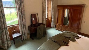 A bedroom with a bed, a wooden wardrobe, a desk with a chair, and a window with curtains. - Sherramore Lodge -  a lodge that sleeps 19 guests  in 10 bedrooms (Laggan)