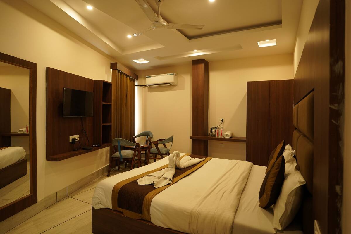 A hotel room with a bed, a TV, a desk, and a chair.