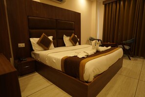A hotel room with a large bed, a wooden headboard, a bedside table with a lamp, and a chair.