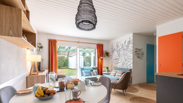 Une cuisine moderne avec une table à manger dressée pour le petit-déjeuner, un canapé et une vue sur le jardin.