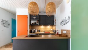 Une cuisine moderne dotée d’un îlot central, de meubles de couleur noire et d’un plan de travail en bois.