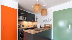 Une cuisine moderne dotée d’un îlot central, d’appareils électroménagers intégrés et d’une porte verte.