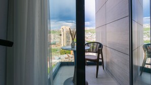 Un balcon donnant sur un paysage urbain, avec une table et une chaise.