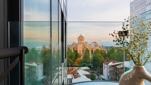 A view from a window with a vase of flowers, a chair, and a building with a dome. - Sunset Apart-Hotel (Yerevan)