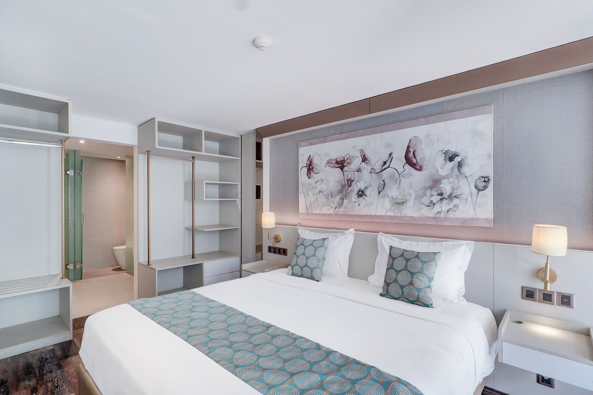 Una camera d'albergo con un letto grande, un armadio, un bagno e un quadro appeso al muro.
