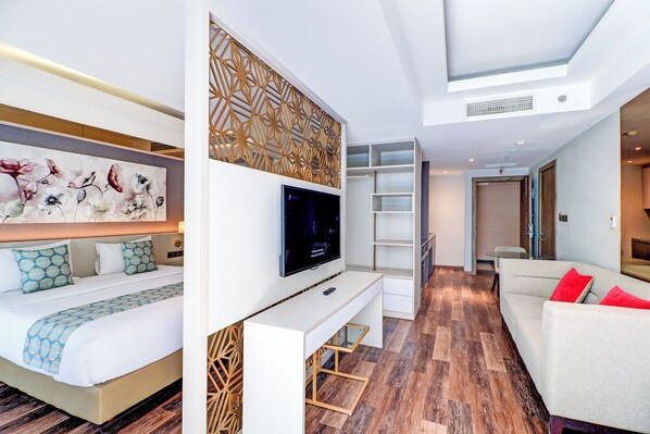 A modern hotel room with a bed, a TV, a desk, and a sofa.