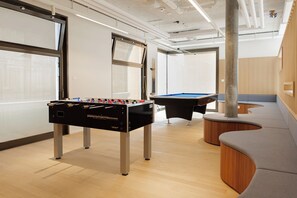 A modern indoor recreational area with a foosball table, pool table, and seating area. - Geneva Youth Hostel (Vernier)