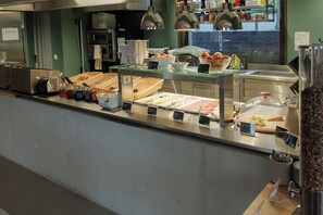 A buffet area with various food items and condiments. - Geneva Youth Hostel (Vernier)
