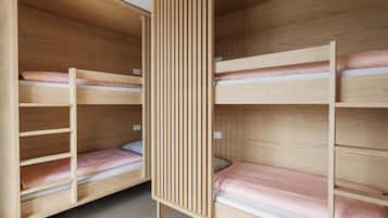 Ein Zimmer mit zwei Etagenbetten, Holzwänden und einer durchbrochenen Trennwand.