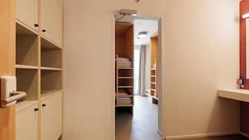 Ein Hotelzimmer mit einem Holzschrank, einem weißen Nachttisch und einer Wand mit roten Fliesen.