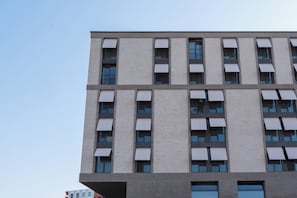 Un immeuble à plusieurs étages doté d’une architecture moderne, caractérisé par une série de balcons et de grandes fenêtres.