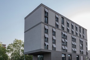 Un bâtiment moderne à la façade plate, doté de nombreuses fenêtres et d’une partie d’angle particulièrement saillante.