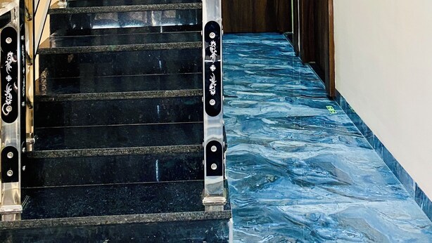 A staircase with black steps and white handrails, leading to a wooden door at the top. - Hotel Shree Sita Ram Kutti (Ujjain)