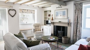 Ein Wohnzimmer mit Kamin, einem weißen Sessel, einer Couch und einem Couchtisch.