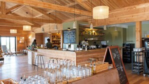 Un interior de madera con zona de bar, asientos y un menú en una pizarra.