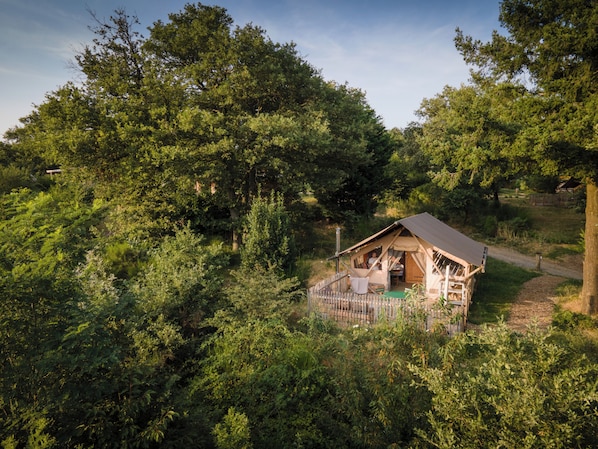 A rustic cabin surrounded by dense forest, with a dirt path leading to it. - Huttopia Pays de Condrieu (Tupin-et-Semons)