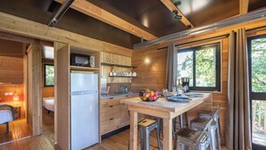 Una cocina funcional con armarios de madera, un refrigerador y una zona de comedor con taburetes.