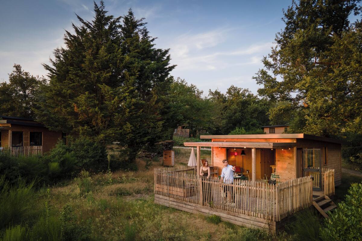 Eine Holzhütte mit einer Terrasse, umgeben von dichtem Wald.