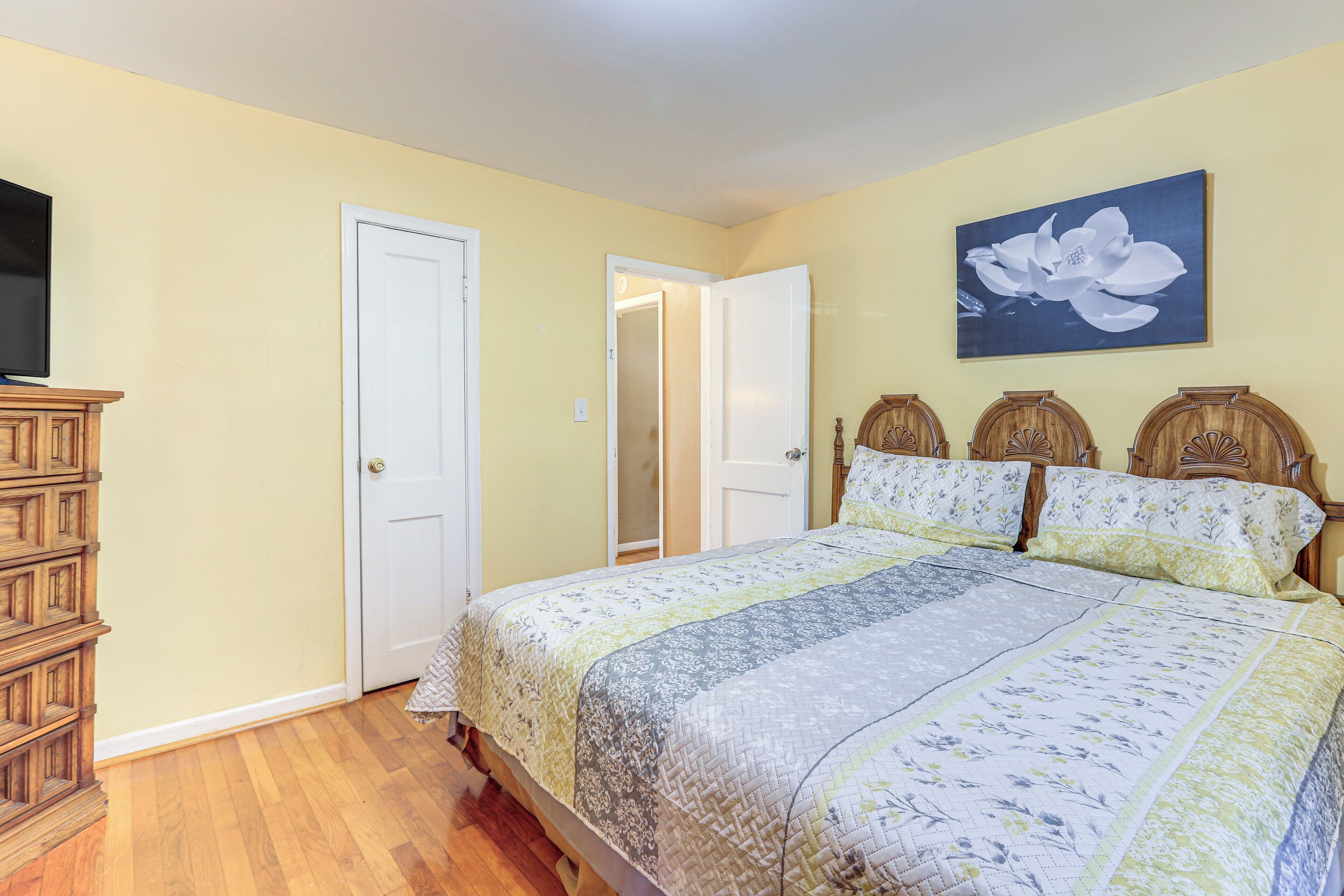 A bedroom with a bed, a dresser, and a television.