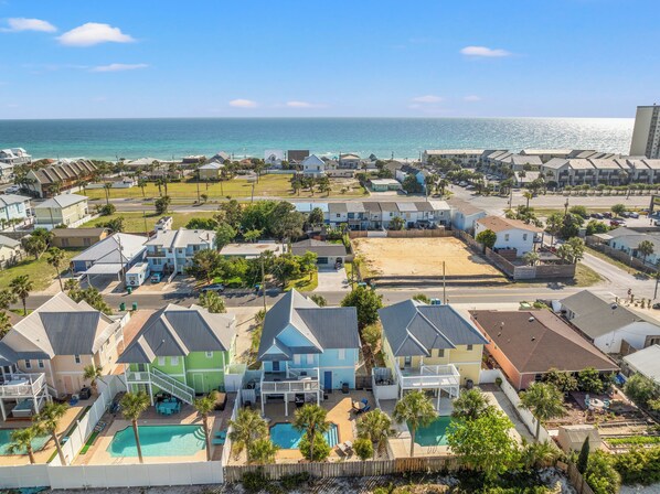 A coastal residential area with houses, a swimming pool, and a view of the ocean.
