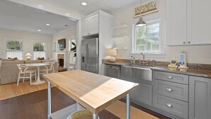 Una cocina moderna con armarios blancos, electrodomésticos de acero inoxidable y una mesa de comedor de madera.