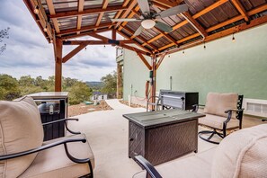 An outdoor patio with a wooden ceiling, a ceiling fan, and string lights. There are two chairs, a table, and a grill. - < 1 Mi to Comal Park: Peaceful Duplex w/ Yard! (Canyon Lake)