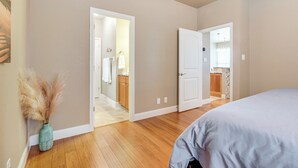 Quarto com uma cama grande, piso de madeira e porta para um banheiro.