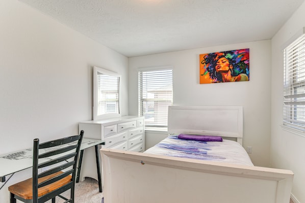 A bedroom with a bed, a desk, a chair, and a dresser.