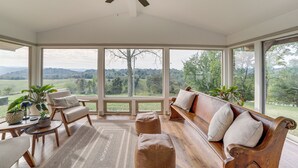 Une véranda avec un banc en bois, des chaises et un ventilateur de plafond.