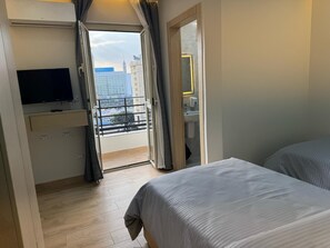 Une chambre d’hôtel avec un balcon, une télévision et une salle de bain équipée d’un miroir et d’un lavabo.