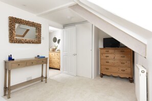 Una habitación con un aparador de madera, un espejo con marco de madera, una puerta blanca y un radiador blanco.