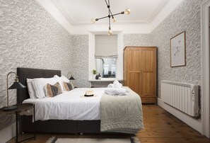 Un dormitorio con cama, mesita de noche, lámpara, armario y radiador.