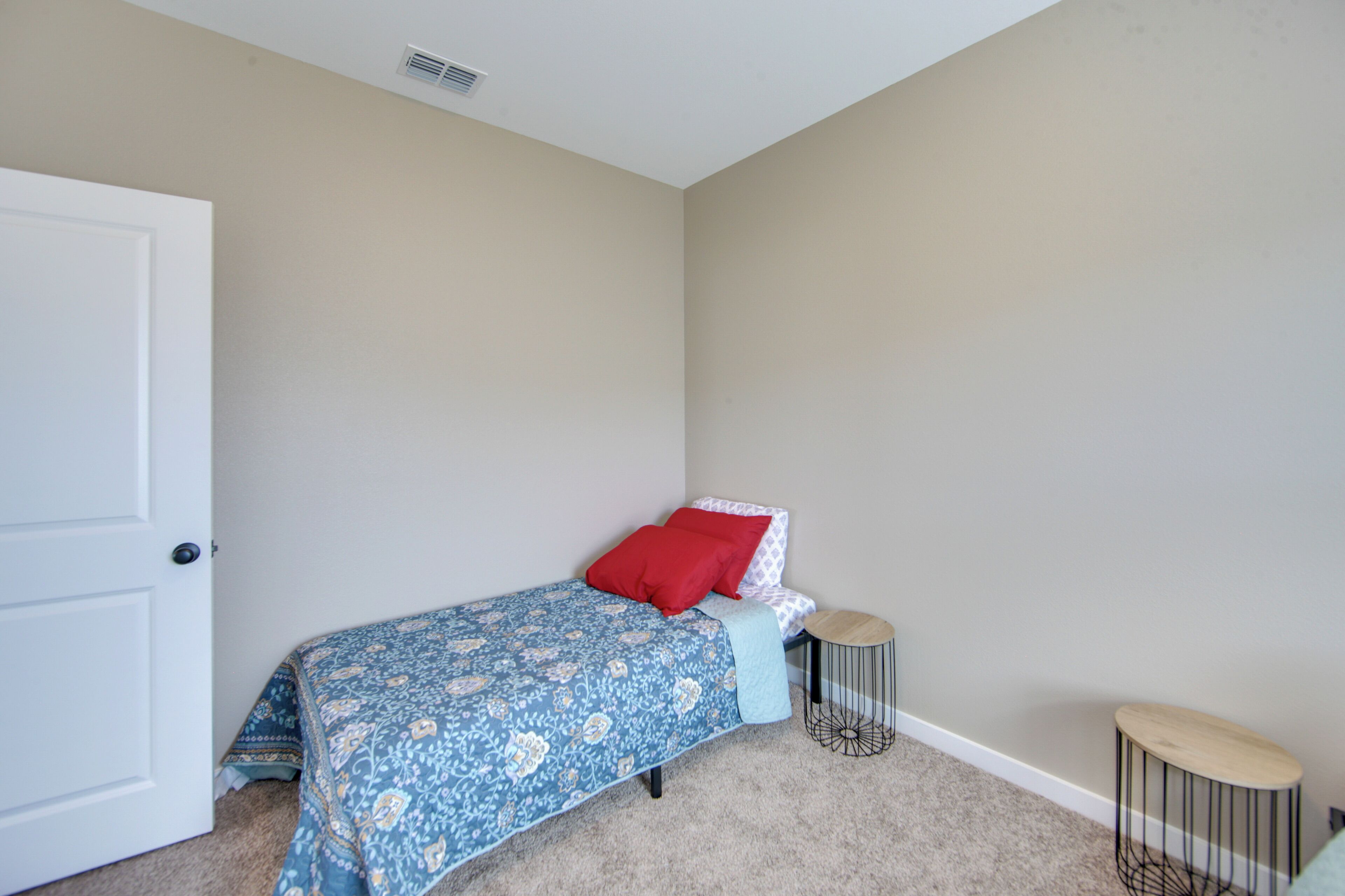 A bedroom with a bed, two side tables, and a door.
