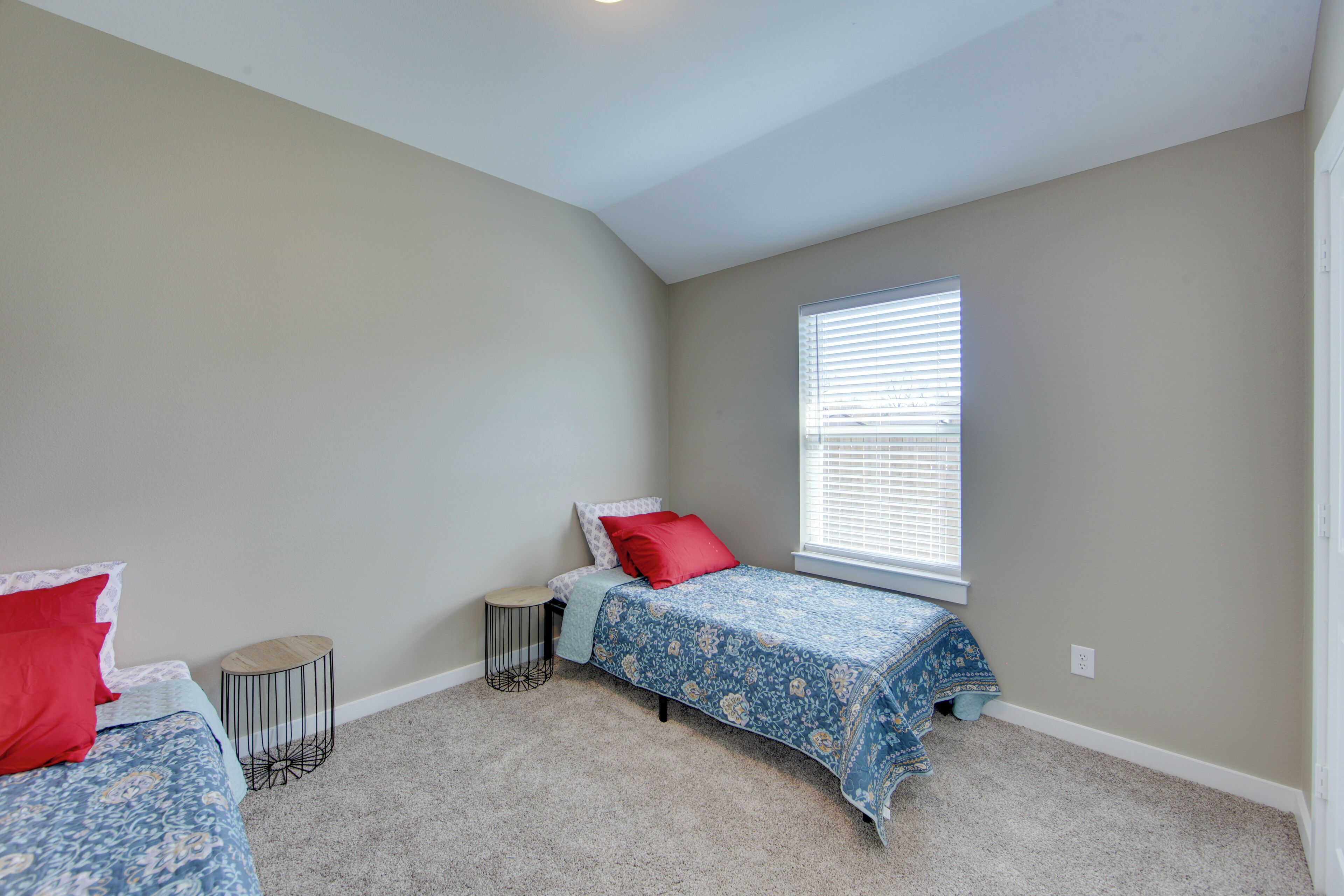 A bedroom with a bed, a small round table, and a window with blinds.