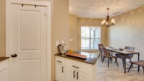 A kitchen with white cabinets, a granite countertop, a dining table with chairs, and a chandelier. - 8 Mi to State Park: Home w/ Fenced Yard in Lindale (Lindale)