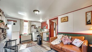 Een knus woongedeelte met kitchenette, een bruine leren bank en een eethoek.