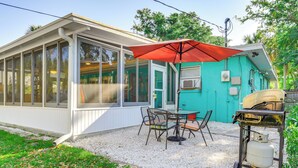 A covered patio with a table and chairs, a red umbrella, and a gas cylinder. - Englewood Bungalow 1 Mi to Beach: Pets Welcome! (Englewood)