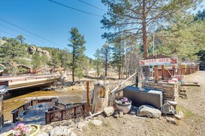A rustic deck area with a sign reading "River Deck," surrounded by natural scenery and a small dock extending into a river. - Private Hot Tub & Deck: Romantic Getaway in Drake (Drake)