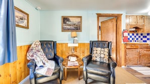 A cozy room with two leather chairs, a small wooden table, and a painting on the wall. - Fish, Hike & Unwind: Drake Cabin w/ Hot Tub! (Drake)