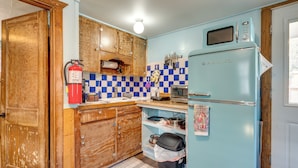 A compact kitchen with wooden cabinets, a blue checkered backsplash, a vintage Galanz refrigerator, and a fire extinguisher. - Fish, Hike & Unwind: Drake Cabin w/ Hot Tub! (Drake)