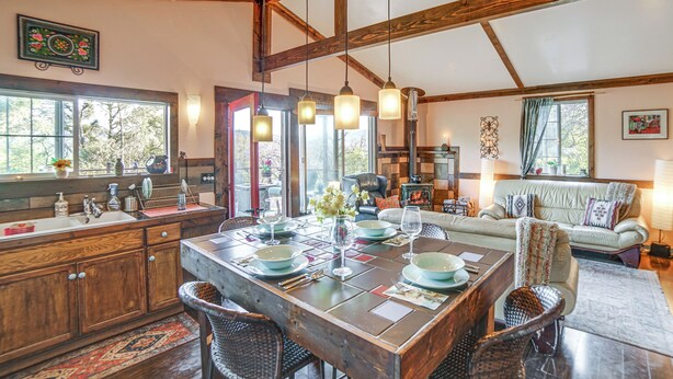 Une cuisine spacieuse avec des poutres apparentes, une table à manger pour quatre personnes et un coin salon confortable avec un canapé et une cheminée.